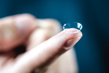 Contact lenses macro close up. Man holding lens on finger. Customer, patient or eye doctor, oculist...