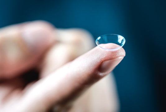 Contact lenses macro close up. Man holding lens on finger. Customer, patient or eye doctor, oculist or optician in clinic. Myopia, eye sight or optometry concept.