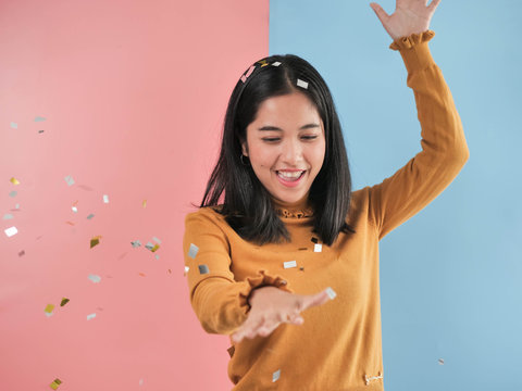 Happy Asian woman with falling silver and golden paper glitter down.
