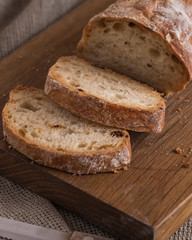Appetizing sliced ciabatta bread on wooden board.