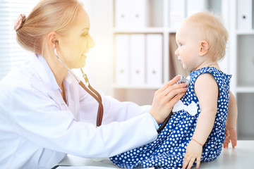 Fototapeta premium Doctor and patient in hospital. Little girl is being examined by pediatrician with stethoscope. Medicine and health care