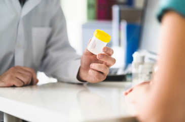 Doctor, patient and urine test cup. Physician giving pee container to a woman in clinic or hospital...