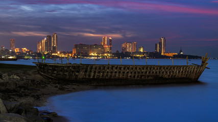 Fototapeta na wymiar Old shipwreck on the beach during sunset at Pattaya city background.
