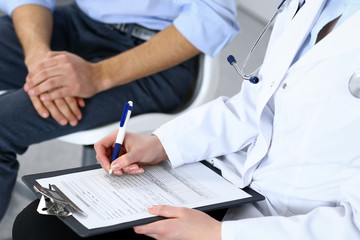 Female doctor holding application form while consulting man patient in hospital. Medicine and healthcare concept