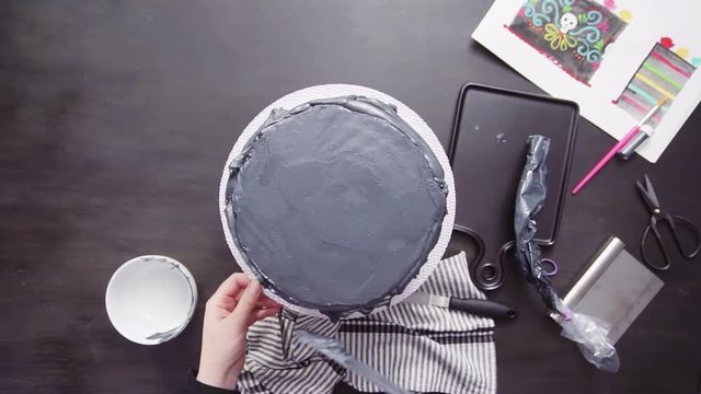 Step by step. Flat lay. Baker frosting multilayer chocolate cake with a black italian buttercream frosting.