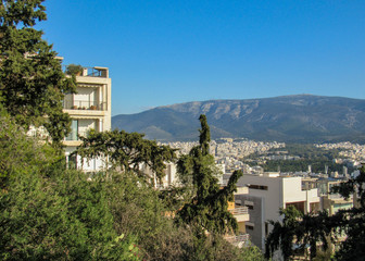 View of Athens city from Mount Hymettus with white buildings architecture, mountain, trees and blue sky