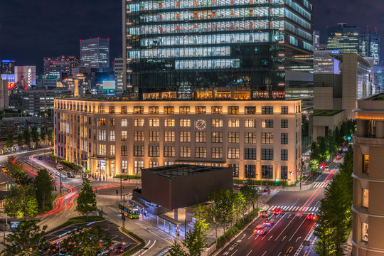 Night view of KITTE commercial facility building deployed by Japan Post in 2013, The GranTokyo and Pacific Century Place Marunouchi skyscrapers overlooking the railroad tracks of Tokyo Station. 