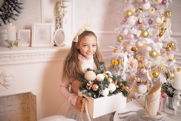 Beautiful little girl in a dress standing near the Christmas tree. Winter holidays. Happy New Year