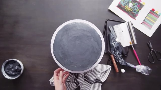 Step by step. Flat lay. Baker frosting multilayer chocolate cake with a black italian buttercream frosting.