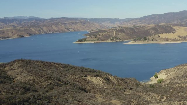 A blue lake in between hills with power boats and kayaks
