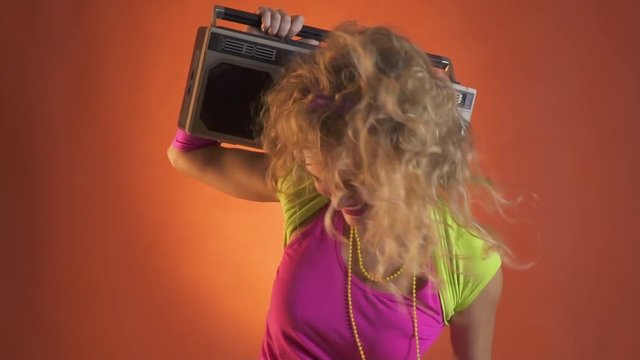 Young blonde woman having fun dancing with the boombox, retro style