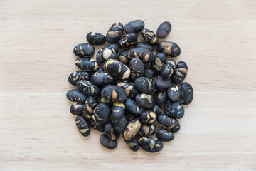 Heap of black shell nuts on wooden background.