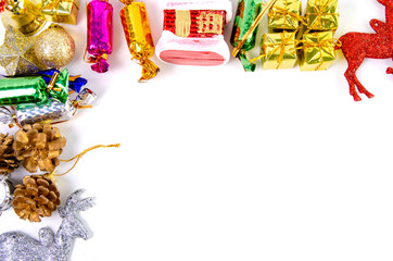 Christmas frame of decor balls, garland, beads, reindeer red pink blue golden decorations on white background. Top view.