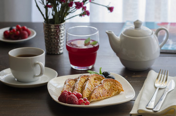 Spanish Torrijas or french toasts with berries and icing sugar for breakfast in hotel restaurant.