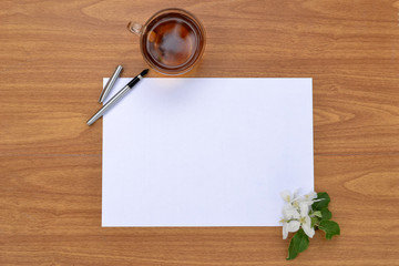 A clean sheet of paper on a wooden surface and a Cup of tea.