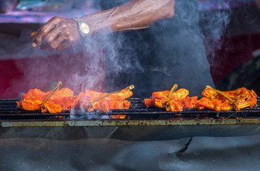 Traditional Thai steak roasted pork. Thai street food. Man roasting slice of meats on the outdoors grill.