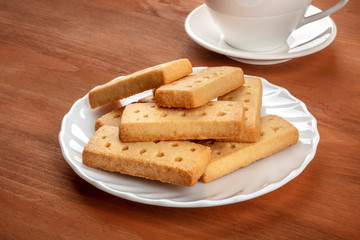A photo of Scottish shortbreads, butter cookies, on a rustic wooden background with a cup of tea and copy space