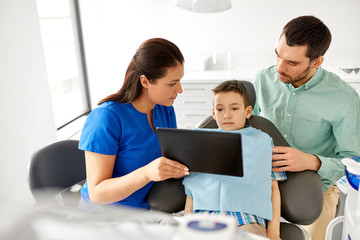 medicine, dentistry and healthcare concept - dentist showing tablet pc computer to kid patient and his father at dental clinic