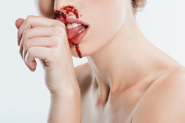 close up of naked woman with injury on face licking blood from hand isolated on white