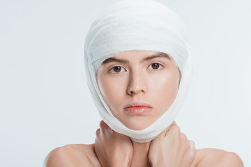 close up of adult woman with bandages on head isolated on white