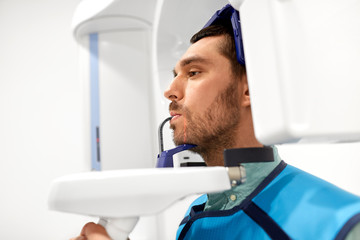 medicine, dentistry and healthcare concept - male patient having panoramic x-ray scanning procedure at dental clinic