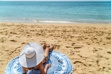 Fototapeta na wymiar Young Woman With White Hat Relaxing On Ocean Beach