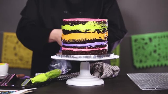 Step by step. Baker frosting multilayer chocolate cake with buttercream frosting.