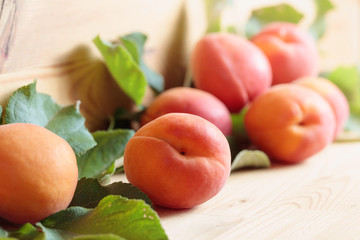 Apricots with leaves on a wooden table.