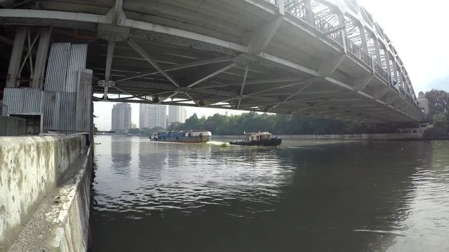 Manila, Philippines - December 5, 2017: Tug Boat Towing Barges On Pasig River toward long span iron bridge.