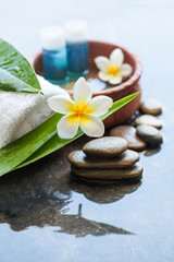 Fototapeta na wymiar Two small bottles with oil. Spa or wellness setting with tropical flowers, bowl of water. Body care and spa concept