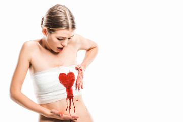 adult woman in bandages looking at bloody heart isolated on white