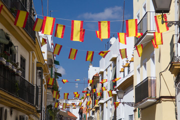 Spanish flags on the street in Seville, Spain. Details of old buildings facade, wall with wooden frame windows.