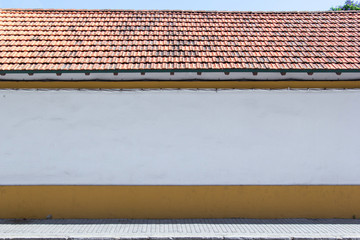 Blank, white wall by the street - clean space as a background for graphical mockup. Orange tile roof.