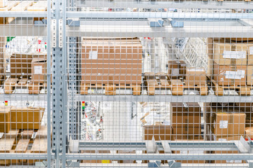 Large cardboard boxes on shelves closed metal mesh in a warehouse in an industrial enterprise. Warehouse technologies, employment at the factory. Arrangement of goods. Parcel delivery.
