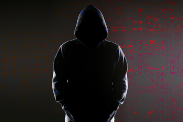 Silhouette of a hacker on black with binary codes on background