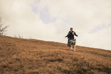 A girl plays with a Husky dog on the top of hill. Ukrainian Carpathian Mountains. Autumn is coming.