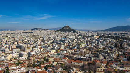 Fototapeta na wymiar Athens from Acropolis showing Mount Lycabettus with white buildings architecture, mountain, trees, blue sky and floating white cloud background