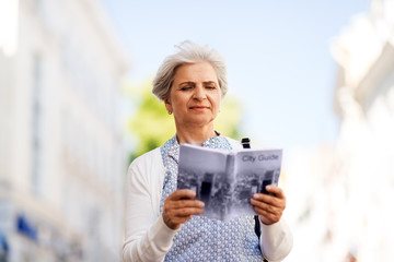 travel, tourism and retirement concept - senior woman or tourist with city guide on street