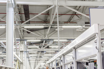 interior of a large industrial workshop, luminescent lamps under the ceiling are suspended in rows. Working atmosphere.