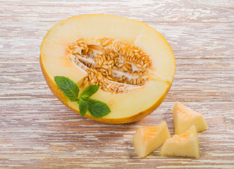 melon with a mint leaf is lying on wooden table