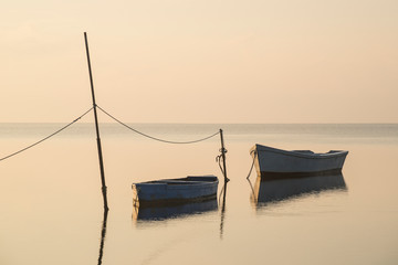 An old traditional fishing boat, moored to a pole in the middle of a coastal lagoon. Picture with a retro style looking.