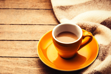 Obraz premium Yellow cup of the coffee and vintage scarf. Photo with filter as a retro color image style.