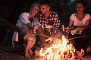 young friends relaxing around campfire