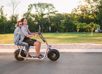 Lovely young couple driving electric bike. Modern city transportation