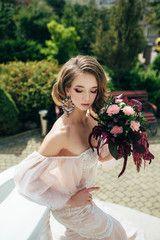 The image of the bride with big earrings. Bride posing on camera