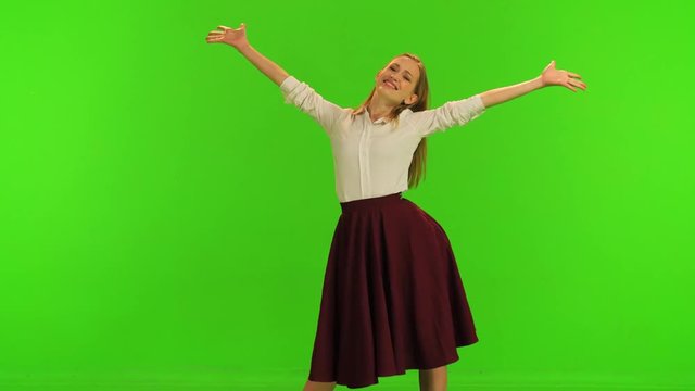 A beautiful dancer poses for the camera, spins and smiles, trying out her dress. Over a green screen.