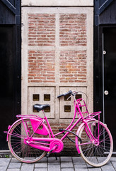 Pink retro bike against brick house entrance