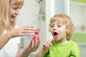 Child toddler brushing his teeth with mother in the bathroom