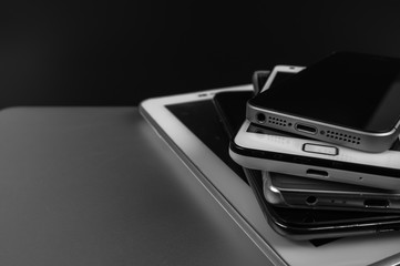 Stack of high-end smartphones on black desk.