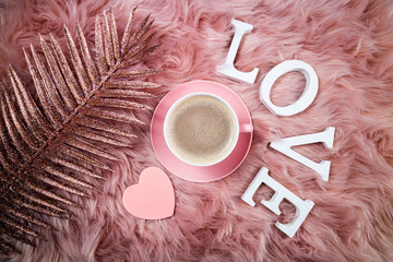 Coffee cup, shiny branch with sparkles and word love on pink woolen fur. Femininity fashion composition. Holidays, valentines day, celebrations, love, trendy and glamor concept